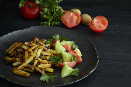 Freshly cooked fried potatoes with onions and mushrooms close-up on a plate. black wood table. horizontalの写真素材