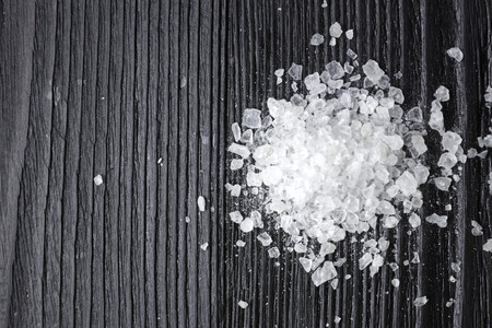 Scattered sea salt on a black wooden table. Copy space, top view.の写真素材