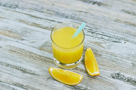 a glass of fresh orange juice with fresh citrus fruits on a light wooden table. horizontal view.の写真素材