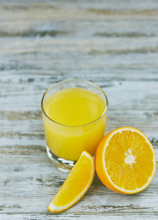 Glass of freshly pressed orange juice with sliced orange half on wooden tableの写真素材