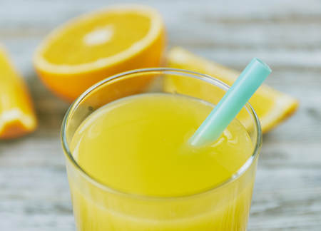 a glass of fresh orange juice with fresh citrus fruits on a light wooden table. horizontal view.の写真素材