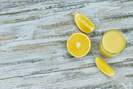 a glass of fresh orange juice with fresh citrus fruits on a light wooden table. horizontal view.の写真素材