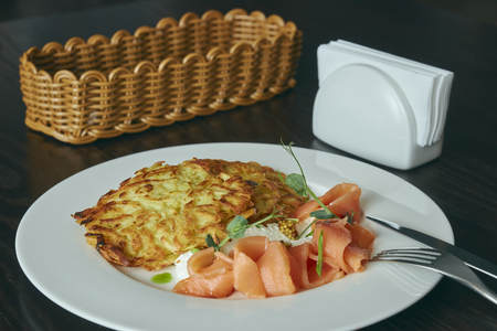 dish Marinated salmon with dill and potato pancakes on a wooden table. fresh salted trout. dish on a plate. Russian food.の写真素材