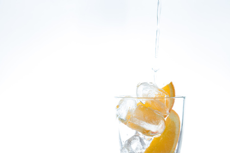 ice drink with orange and ice in the studio on a white background. a stream of water pours intoの写真素材