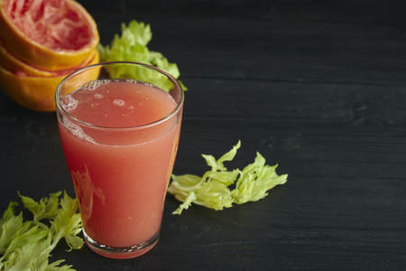 fresh citrus grapefruit juice in a glass. On a black wooden table. Black background. horizontal view.の写真素材