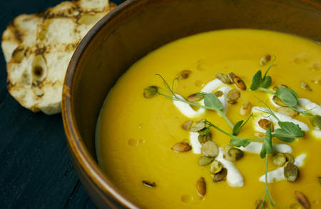 Pumpkin soup in a bowl with cream and pumpkin seeds. Vegan soup. Dark wooden backgroundの写真素材