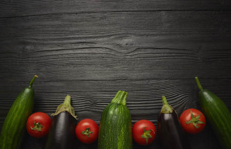 Mix zucchini tomato from fresh raw vegetables on a dark background close-up view from above. empty place. black woodenの写真素材