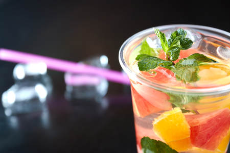 Summer refreshing cocktails with citrus and mint. orange and grapefruit segments. drink on a black table with ice cubes.の写真素材