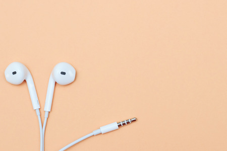 Headphones on a pastel background. White headphones on a peach background. View from above. Copy space Trendy colorful photo. Minimal style with colorful paper background. Music conceptの写真素材