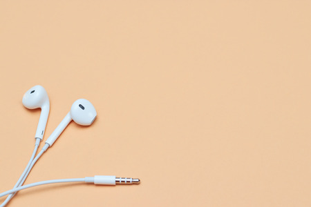 Headphones on a pastel background. White headphones on a peach background. View from above. Copy space Trendy colorful photo. Minimal style with colorful paper background. Music conceptの写真素材