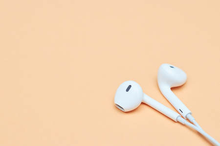 Headphones on a pastel background. White headphones on a peach background. View from above. Copy space Trendy colorful photo. Minimal style with colorful paper background. Music conceptの写真素材