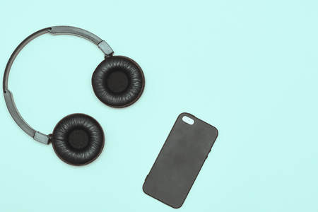 Modern black wireless headphones on a blue background. The concept of music and fashion. Minimalism. copy space. space for textの写真素材