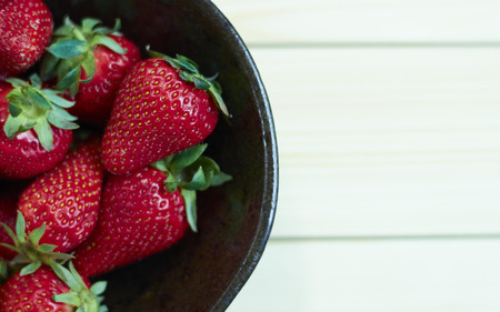 Fresh strawberries on wooden bowl. Sackcloth background. Copy writing space.の写真素材