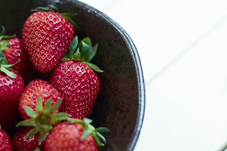 Fresh strawberries on wooden bowl. Sackcloth background. Copy writing space.の写真素材