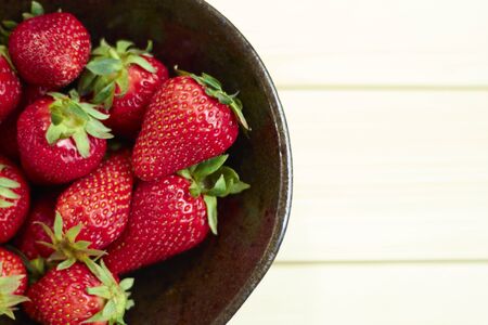 Fresh strawberries on wooden bowl. Sackcloth background. Copy writing space.の写真素材