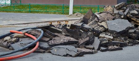 Old broken asphalt in the yard in the city. Road. terrible roads. road repair. problemsの写真素材