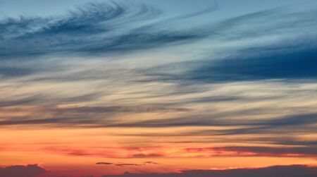 Dramatic red and orange sky and clouds. Red-orange clouds at sunset sky. Warm weather background. Art photo of the sky at dusk. Sunset abstract background.の写真素材