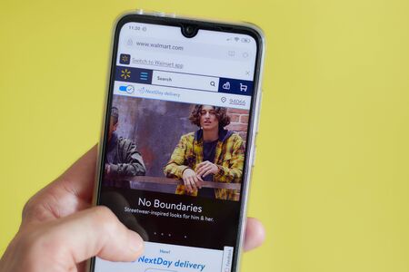 Walmart website homepage. Walmart logo visible on the iphone screen. Walmart Is an American company managing the world's largest wholesale and retail chain. Los Angeles,のeditorial素材