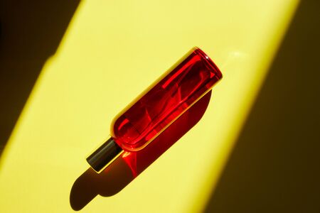 red bottle with shadow effect isolated on a yellow background. The concept of female cosmetics and body care.の写真素材