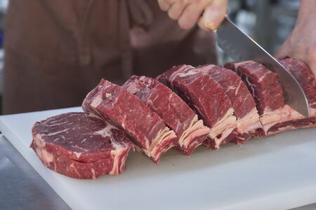 Butcher cutting beef in the kitchen. Closeup of hands with a knife and meat.の写真素材