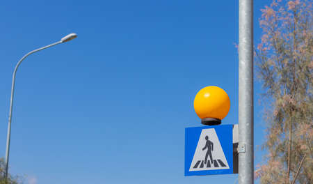 pedestrian crossing road sign on a background of blue sky. warning sign for drivers.