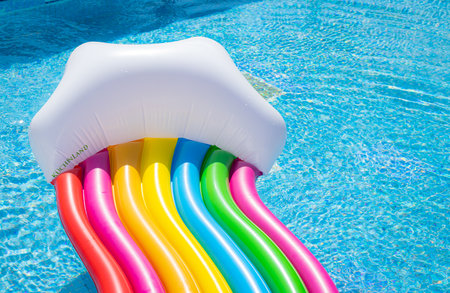 Inflatable mattress, rainbow colors. swimming in the pool on a sunny day. fun in the poolの写真素材