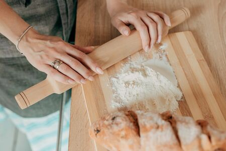 Beautiful housewife in a stylish apron cooks in a cozy kitchen. Close-upの写真素材
