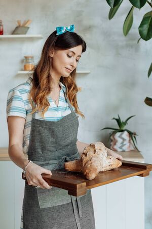 Beautiful housewife in a stylish apron cooks in a cozy kitchen.の写真素材