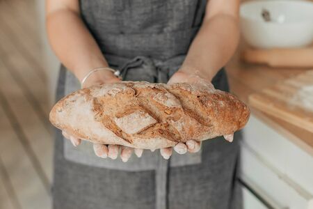 Beautiful housewife in a stylish apron cooks in a cozy kitchen. Close-upの写真素材