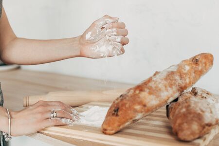 Beautiful housewife in a stylish apron cooks in a cozy kitchen. Close-upの写真素材
