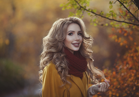 Beautiful autumn portrait of a young smiling mother. Young happy woman in autumn clothes walking in the Park.の写真素材