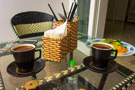 Coffee in a cup on the table with wicker basketの写真素材