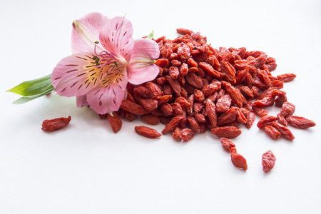 Heap of dried goji berries on white with flowerの写真素材