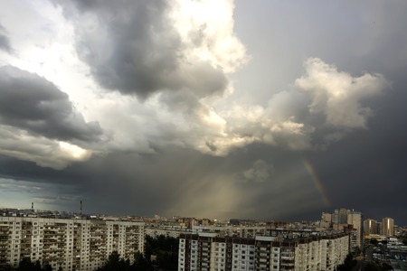 Clouds are illuminated by solar rays, the rainbow in the sky, residential areaの写真素材