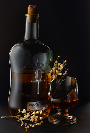 Still-life from a bottle of whiskey, broken glass and dry flowersのeditorial素材