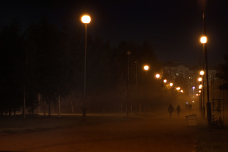 Misty alley, lighted lamps, receding into the distance couple holding handsの写真素材