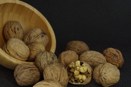 Walnuts are poured from a bowl, one chopped with a core inside. Healthy eating, good for the brain.の写真素材