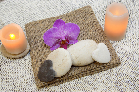 Stones for massage, candles and a flower of orchids on natural natural napkins, pleasant tones, a spaの写真素材