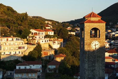 Dawn in a small town, the sun illuminates a stone chapel with a red tiled roof.の写真素材