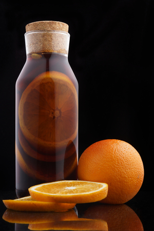 Mulled wine in a bottle with a cork next to an orange on a black background.の写真素材