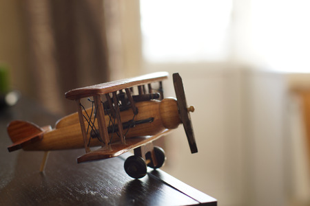A toy wooden plane on the edge of the shelf in the room.