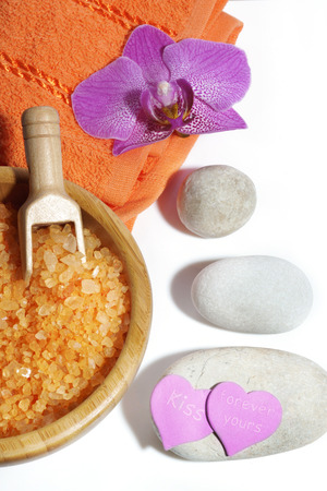 Spa set of orange bath salts, massage stones, towel and orchid flower.の写真素材