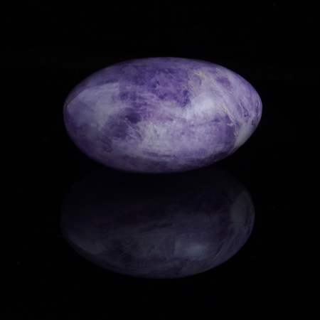 Smooth treated amethyst stone on a dark background with reflection.の写真素材
