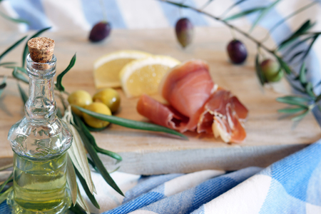Bottle with olive oil on a breakfast background with olives and bacon in the morning.