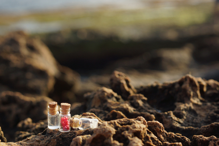 Glass jars filled with stoppers, filled for spa treatments, on rocks near the sea in the morning.の写真素材