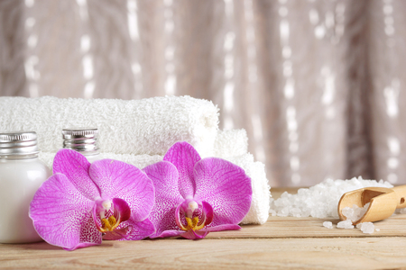 Preparation for spa procedures, salt, towels, lotion and bright flowers of orchids on the tableの写真素材