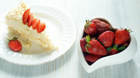 Strawberries on a piece of Napoleon cake and in a bowl in the shape of heart, sweet dessert and berries.の写真素材