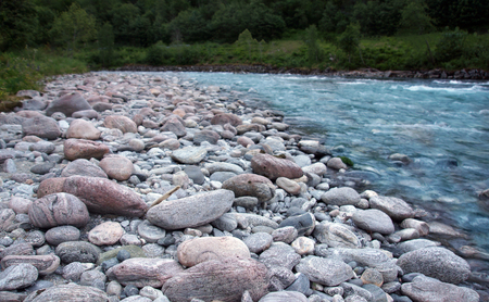 Large granite pebbles on the shore of a clean blue river in Norwayの写真素材