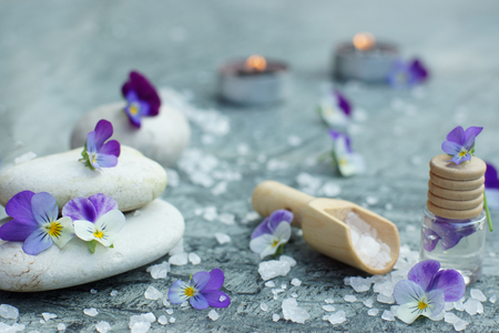Spa still life with white stones, candles, sea salt in the scapula and flowers of pansies on a green marble table.の写真素材
