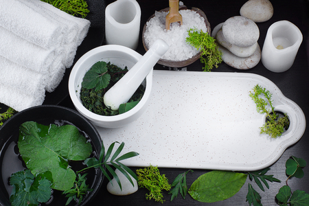 Spa set with towels, stones and white electric candles surrounded by green leaves of plants. Copy space for text.の写真素材